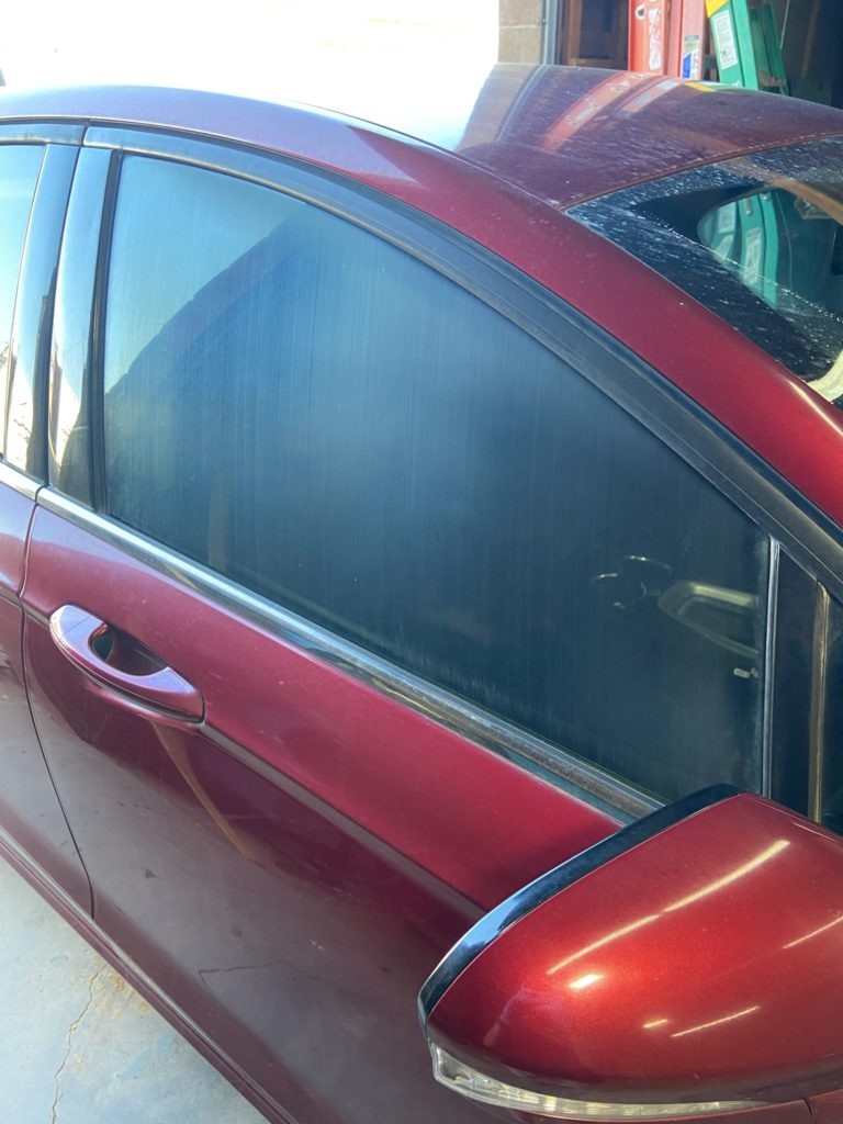 Before automotive acid wash: hard water spots and acid rain etching hazing a car door window