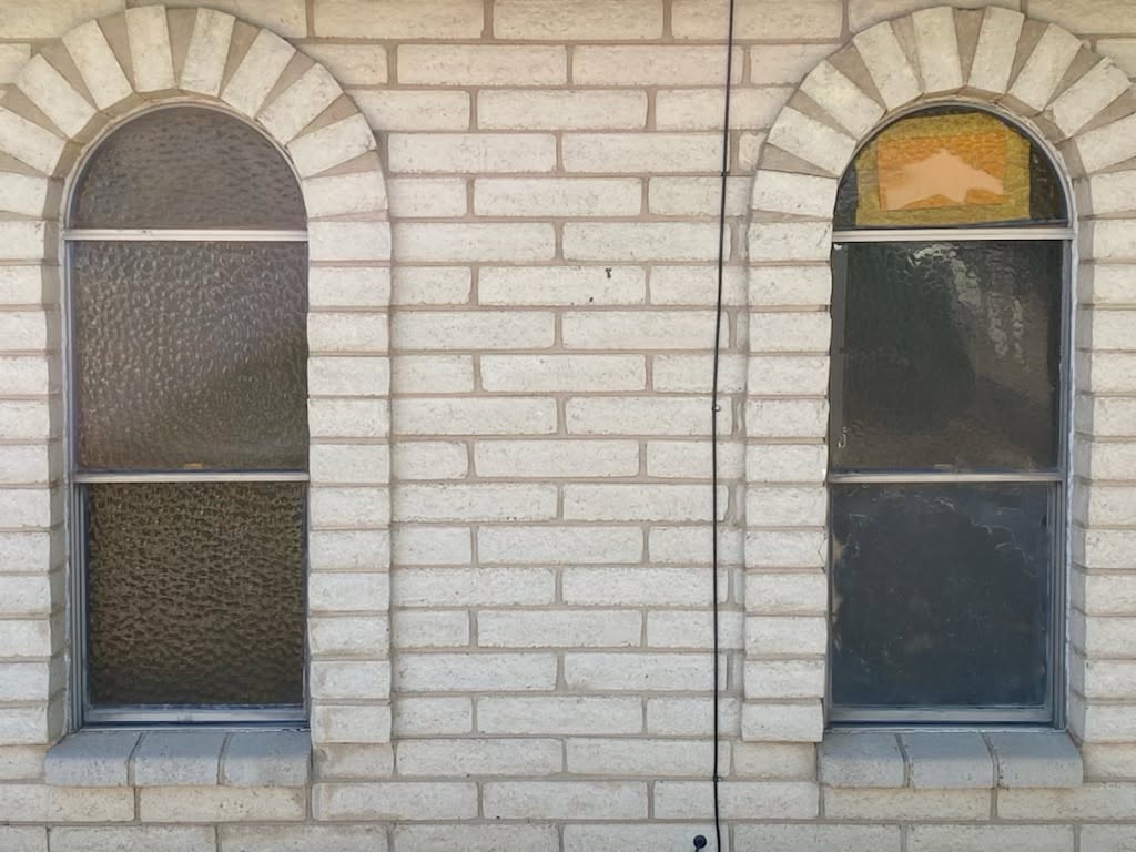 Arched brick windows with old obscure and failed glass before replacement
